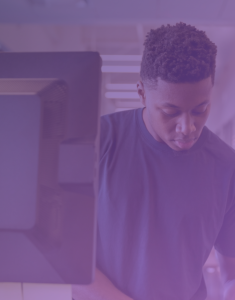 An individual sits at a computer, navigating through screens with ease, symbolizing the streamlined workflow of CISOs and IT managers in simplified compliance management.