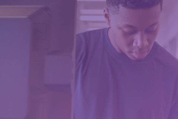 An individual sits at a computer, navigating through screens with ease, symbolizing the streamlined workflow of CISOs and IT managers in simplified compliance management.