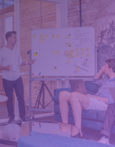 A person standing at a whiteboard, passionately explaining cybersecurity concepts to attentive colleagues. The image reflects an engaging educational session aimed at enhancing employees' understanding of cybersecurity practices and fostering a secure workplace environment.